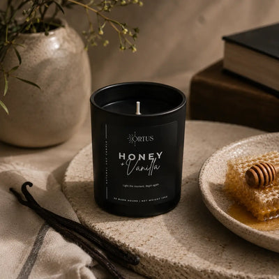 Ortus Honey Vanilla candle on a table with honeycomb and vanilla beans.